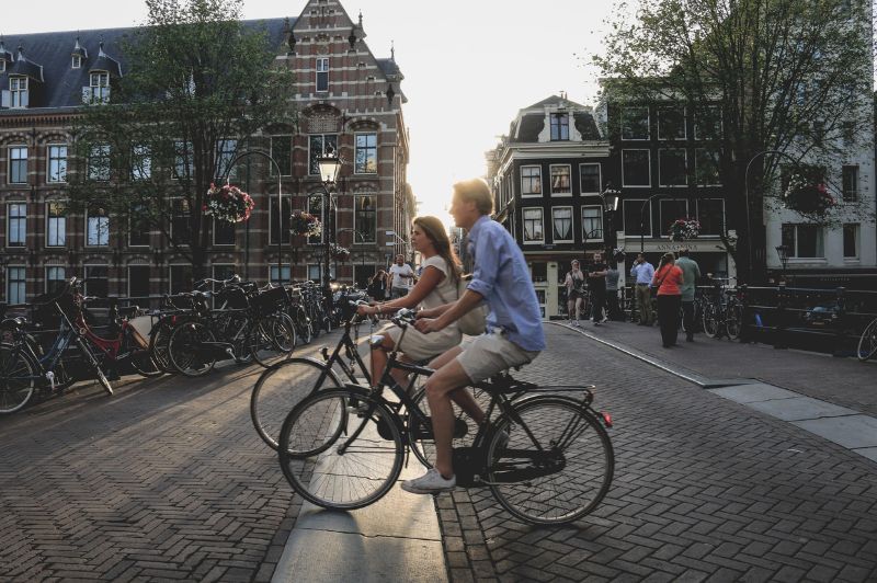 Cyclists riding along the canal path in amsterdam.