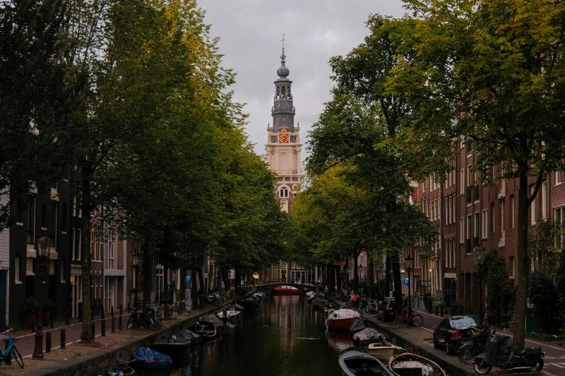 Peaceful amsterdam canal with reflections of historic buildings in the water.