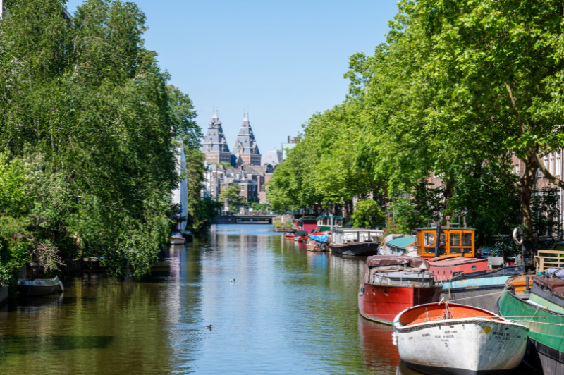Sunny summer view of the canals in amsterdam near the ambassade hotel, with boats and historic canal houses.