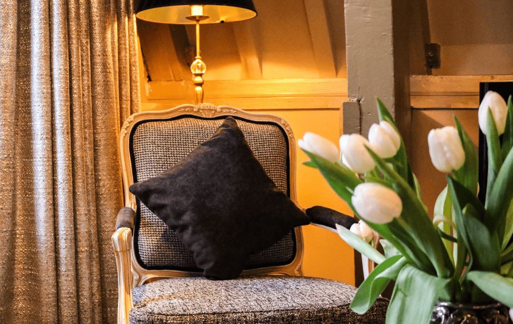Eleganter Stuhl mit einer Vase Tulpen in einer Suite im Ambassade Hotel.
