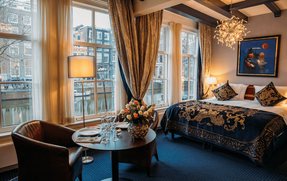 Gemütliche Ecke des Superior Canal View Deluxe Zimmers im Ambassade Hotel mit komfortablen Sitzgelegenheiten und Blick auf den Kanal.