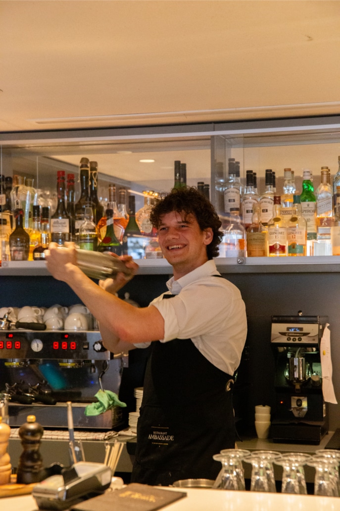 Bartender shaking a cocktail behind the bar.