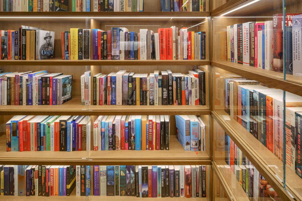 Bookshelves filled with the ambassade hotel’s book collection, featuring works by international authors and artists.