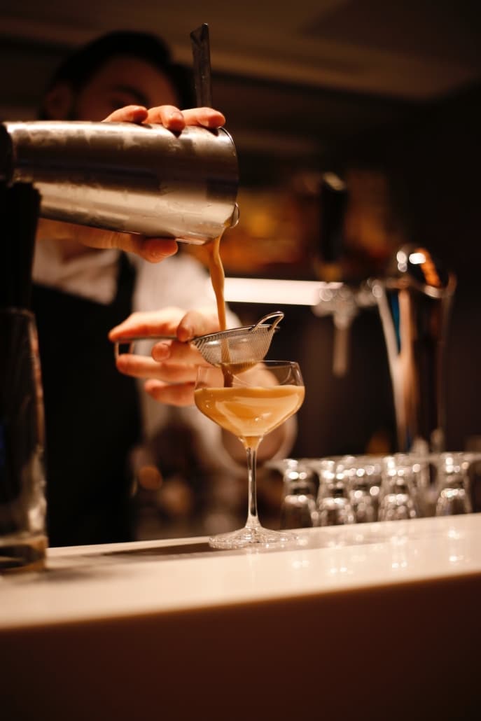 Bartender preparing an espresso martini in the library bar at the ambassade hotel.