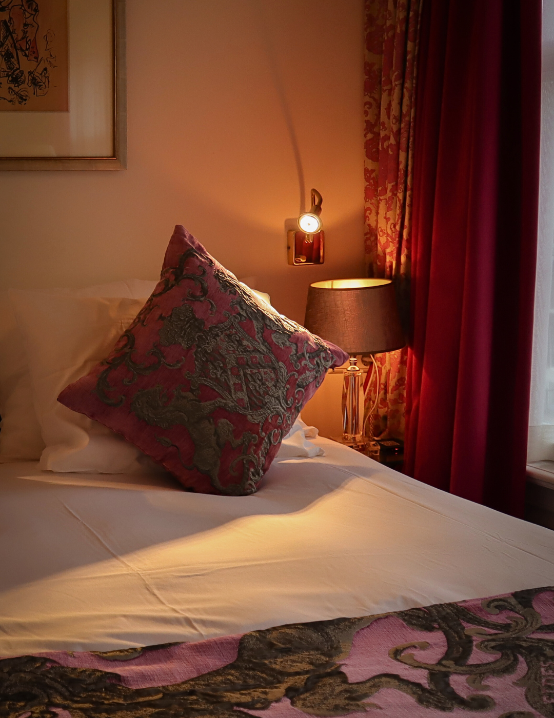 Lampe de chevet chaude allumée à côté d’un lit confortable dans une chambre de l’hôtel Ambassade à Amsterdam.