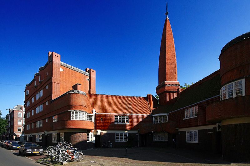 Bâtiment présentant le style architectural de l’École d’Amsterdam avec maçonnerie en briques et détails décoratifs.