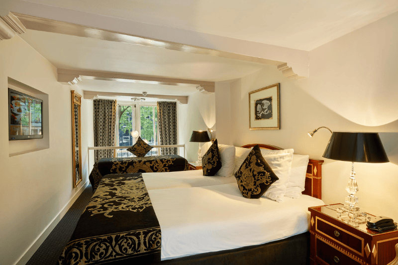 Chambre sur deux niveaux avec vue sur le canal à l’Ambassade Hotel à Amsterdam, comprenant deux étages et de grandes fenêtres donnant sur la Herengracht.