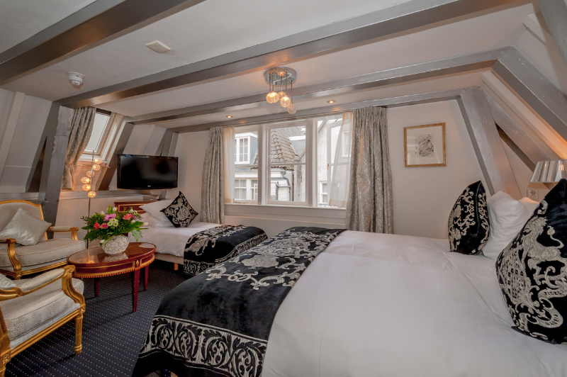 Chambre triple confortable pour trois personnes à l’Ambassade Hotel à Amsterdam avec une décoration élégante et un espace généreux.