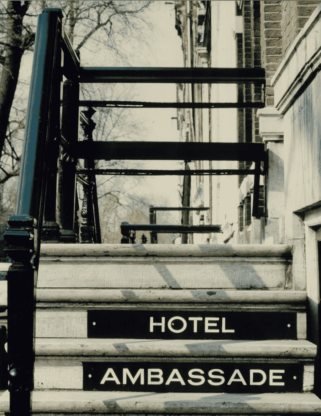 Photo vintage de l'escalier et de l'entrée de l'hôtel Ambassade à Amsterdam, mettant en valeur des détails architecturaux historiques.