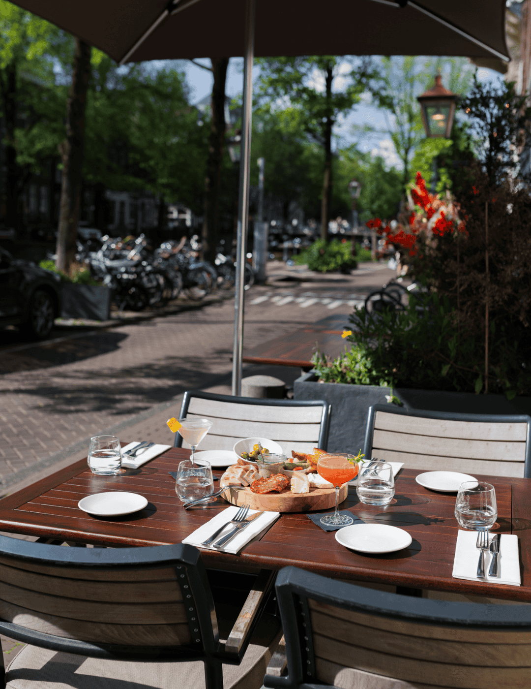 Table baignée de soleil, dressée pour le dîner sur la terrasse de l’Ambassade Hôtel.