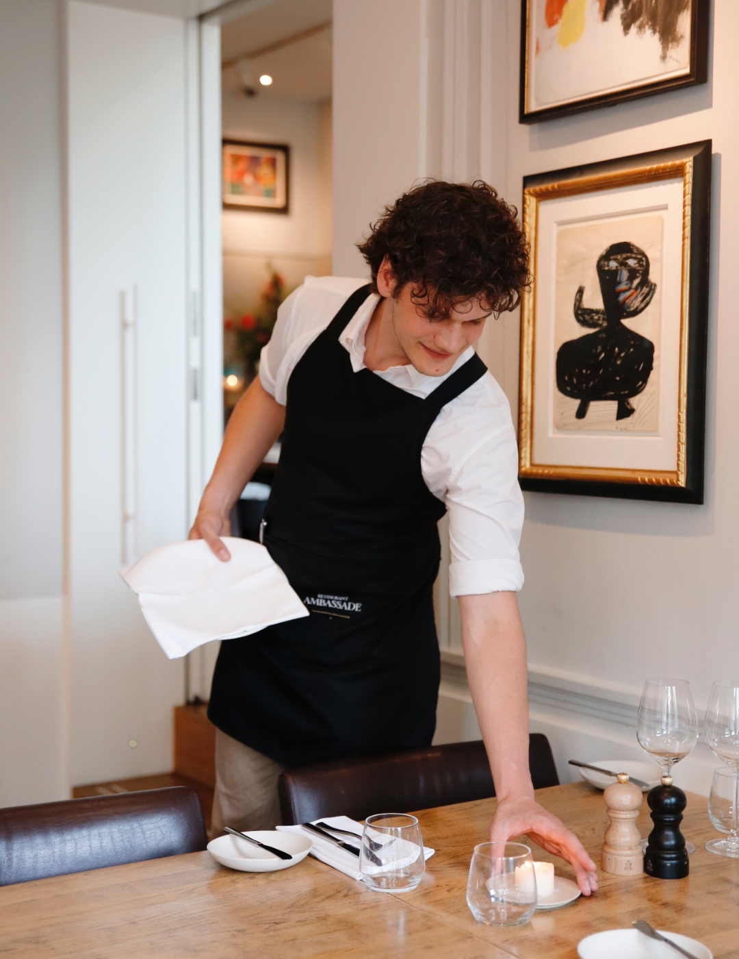 Staff member setting a table in brasserie ambassade.