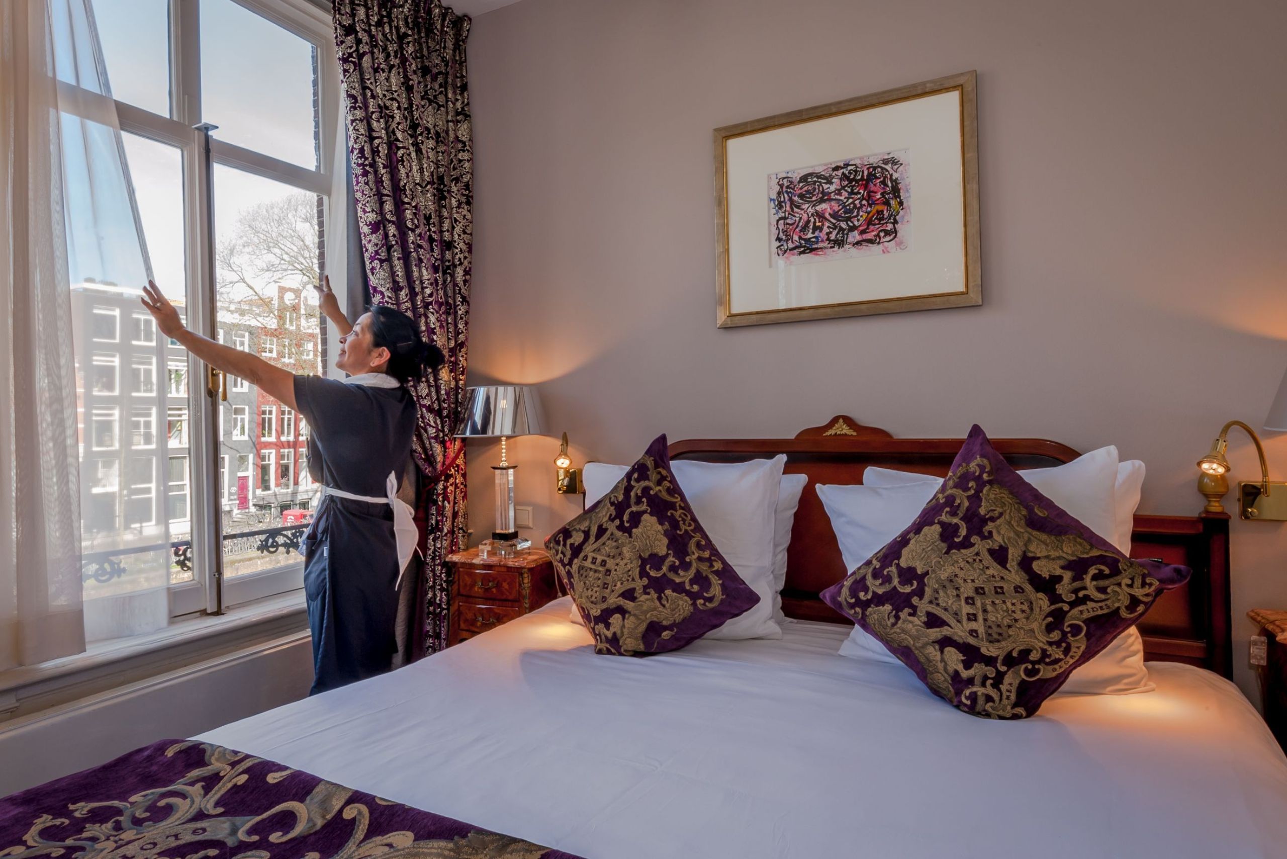 Housekeeping staff member cleaning a room at the ambassade hotel.