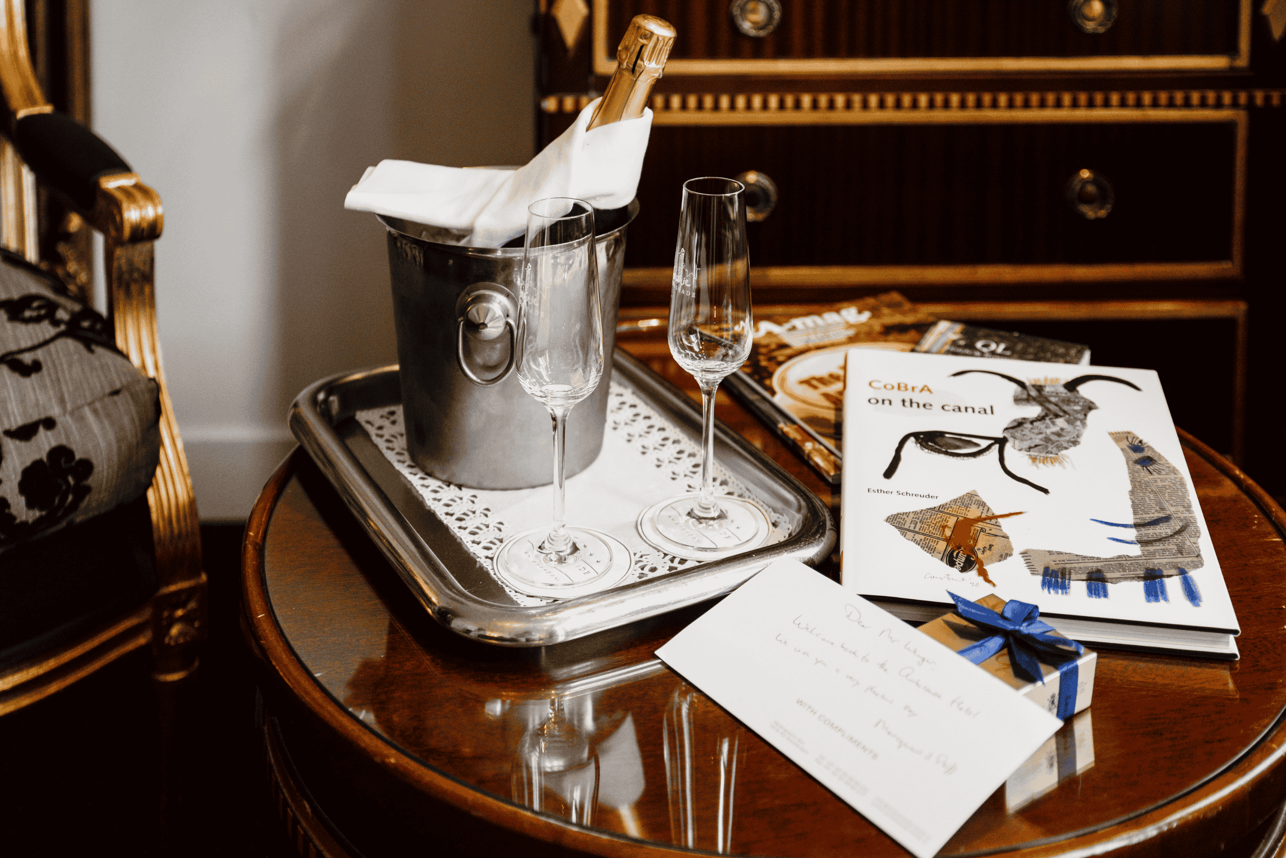 Un client profite de l’expérience avec une coupe de cava et un livre d’art à l’Hôtel Ambassade à Amsterdam.