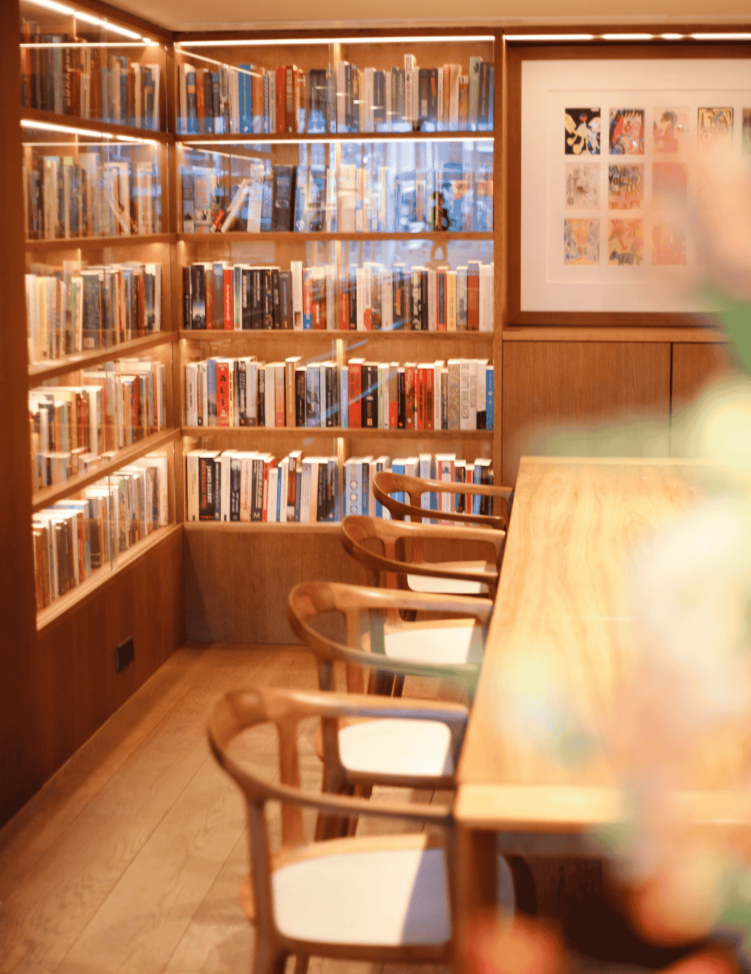 Le Library Lounge de l’Ambassade Hotel avec des livres, des œuvres d’art et des sièges élégants.
