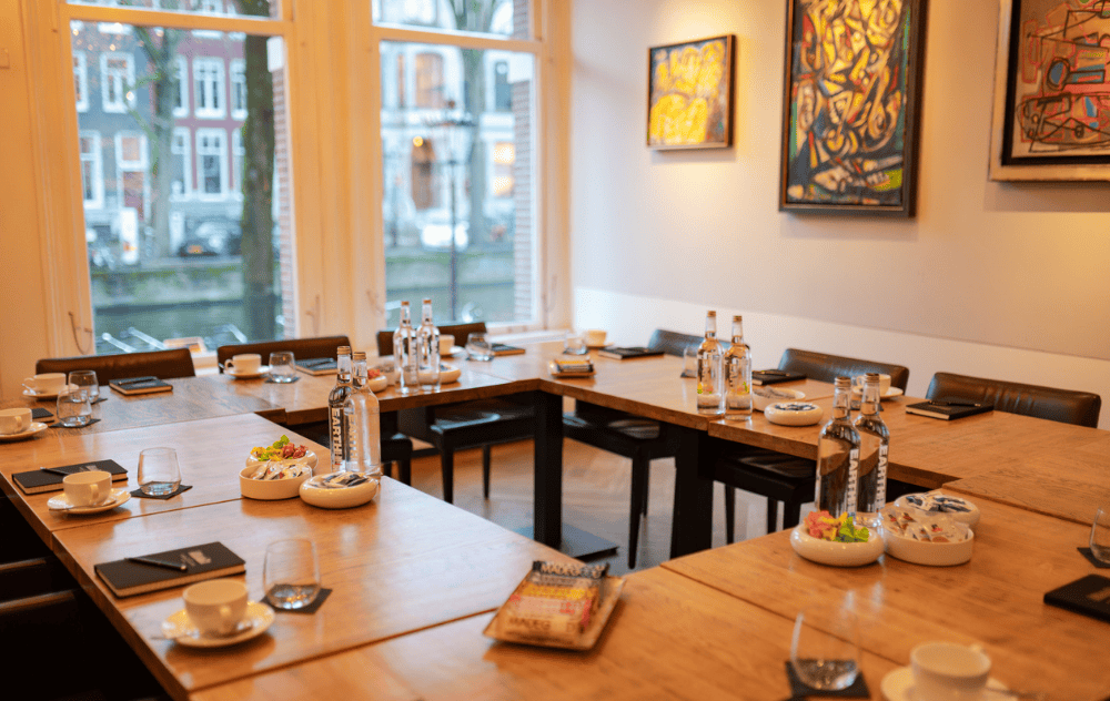 Lounge Alechinsky à la Brasserie Ambassade à Amsterdam, aménagée en forme de U pour une réunion, entourée d’art contemporain.