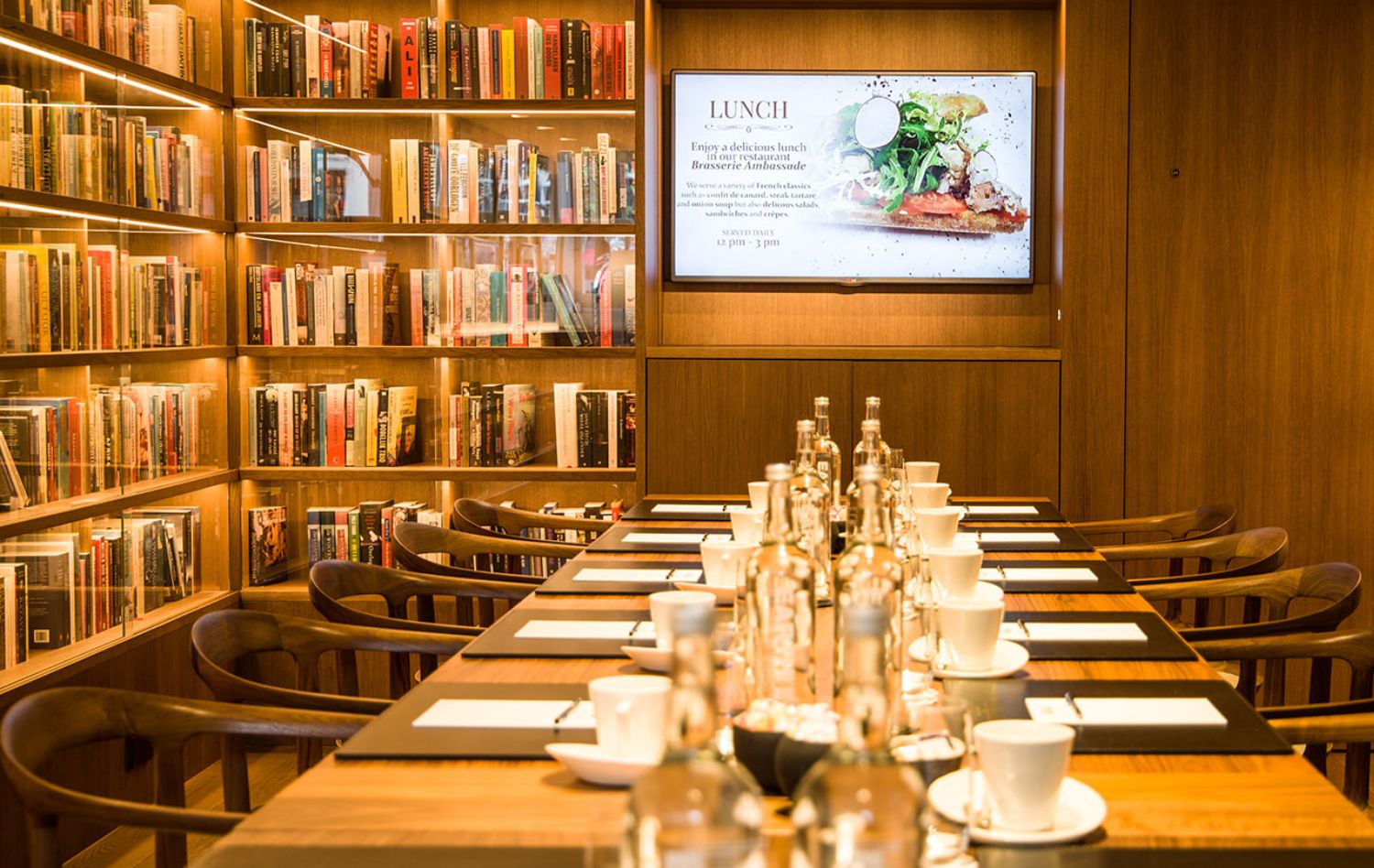 Configuration de présentation dans le bar bibliothèque de l’hôtel Ambassade, entouré de livres et d’art.