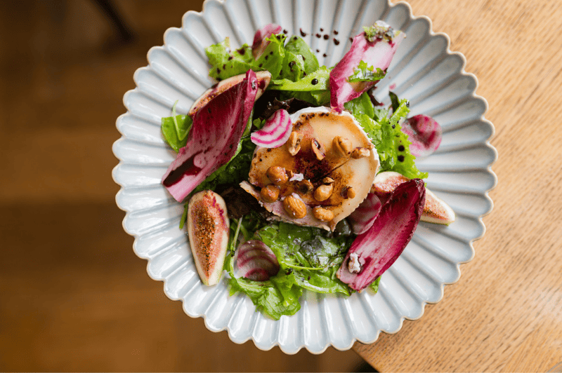 Salade de chèvre et figues servie à la Brasserie Ambassade à Amsterdam, combinant des légumes frais avec des figues sucrées et du fromage crémeux.