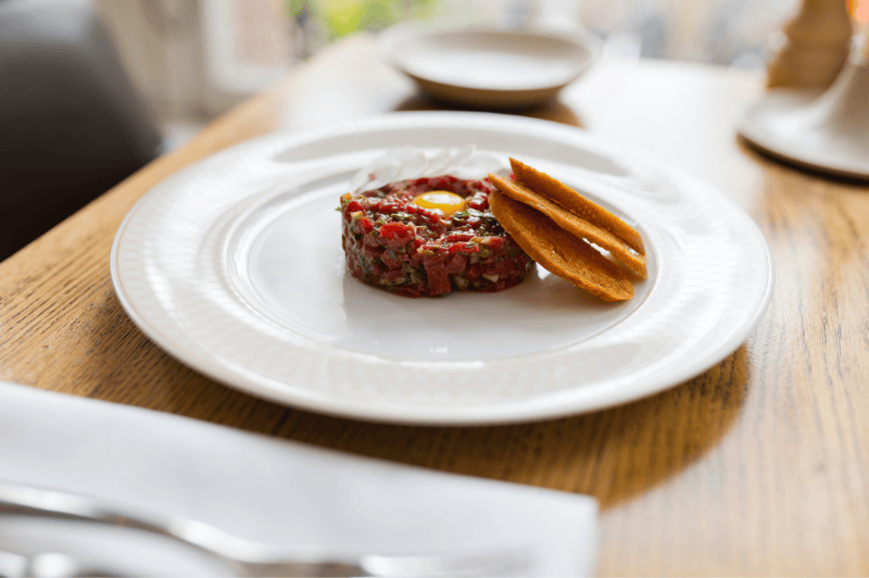 Steak tartare servi à la Brasserie Ambassade à Amsterdam, présenté avec des garnitures classiques.