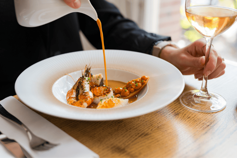 Bouillabaisse servie dans un bol à la Brasserie Ambassade à Amsterdam, mettant en valeur la cuisine classique française de fruits de mer.