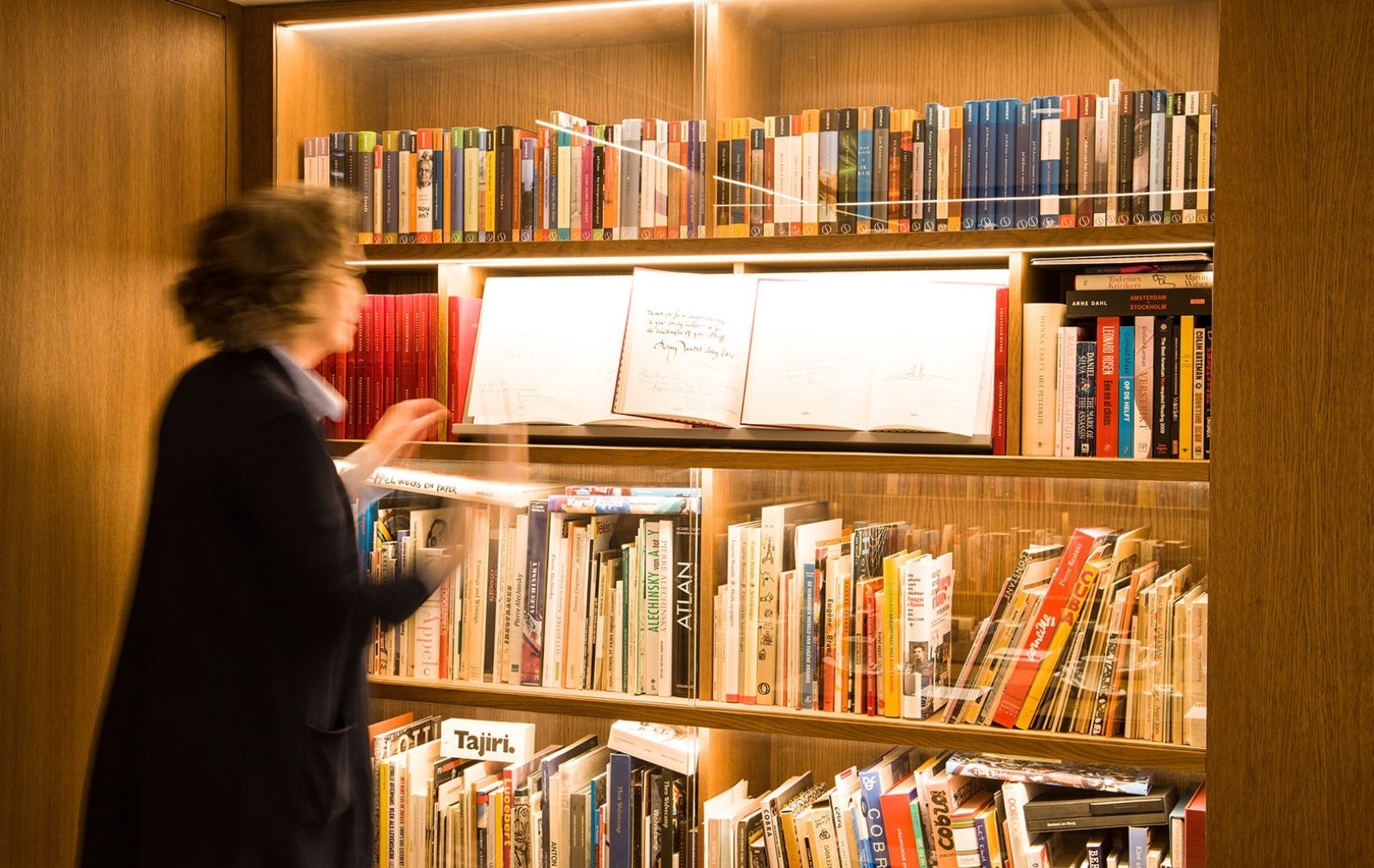 Un invité lisant le livre d’or dans le bar bibliothèque chaleureux de l’hôtel Ambassade à Amsterdam.