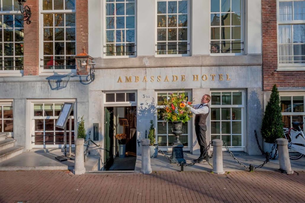 Prachtige bloemstukken bij de ingang van het Ambassade Hotel, die extra elegantie geven aan de gevel aan de gracht.
