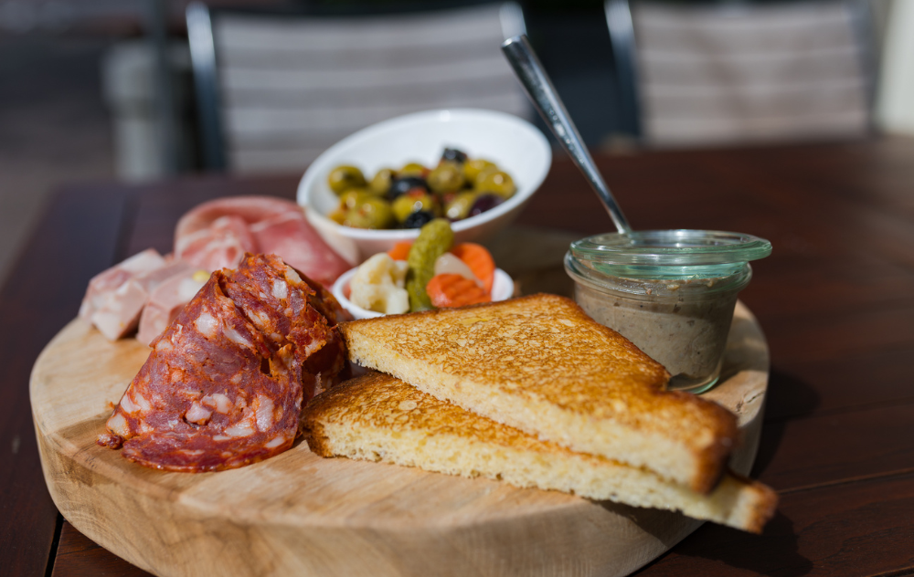 A selection of charcuterie meats, amsterdam pickles, and fresh bread served on the terrace at ambassade hotel.