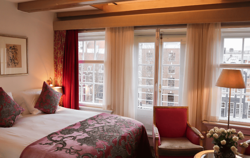Chambre Deluxe avec vue sur le canal à l’Ambassade Hotel, avec mobilier élégant et vue sur les canaux d’Amsterdam.