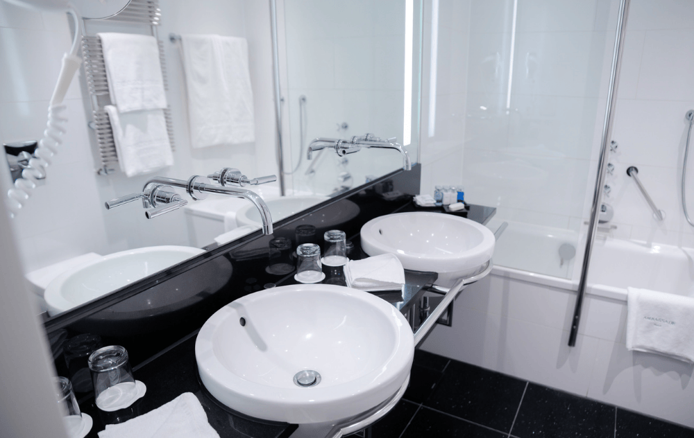 Salle de bains avec double vasque et douche dans la baignoire à l’Ambassade Hotel.