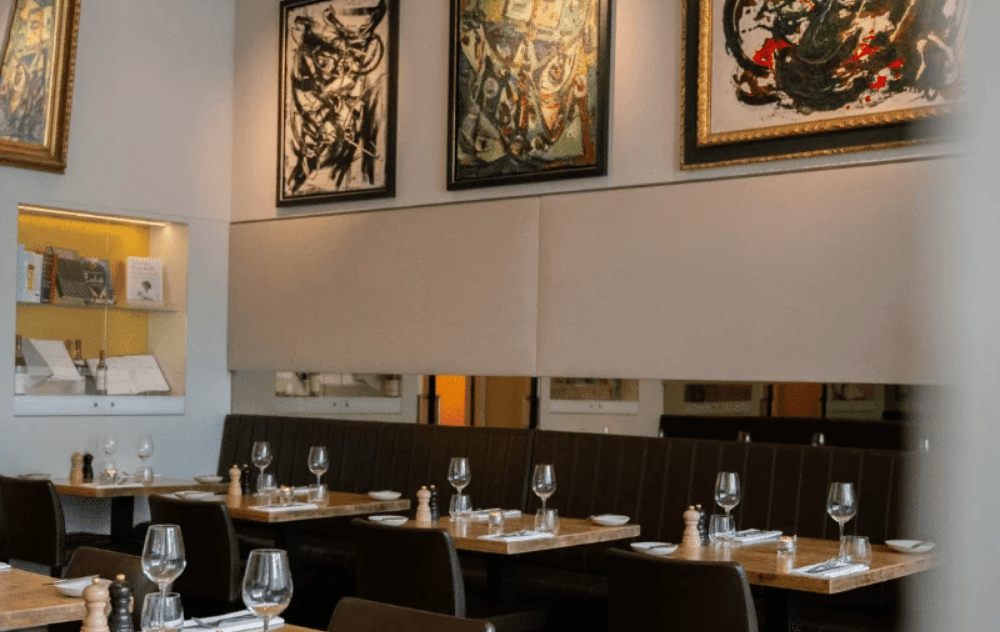 Tables à la Brasserie Ambassade, entourées de miroirs décoratifs et d'œuvres marquantes du mouvement CoBrA.