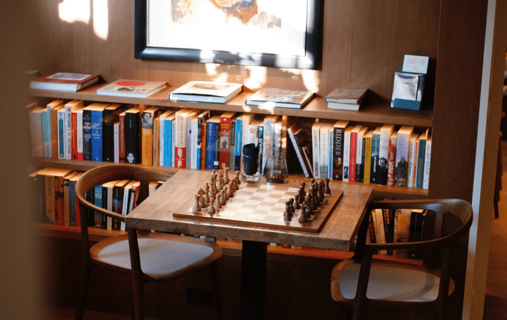 Hall d’hôtel rempli d’art à l’Hôtel Ambassade à Amsterdam, avec mobilier élégant et présentoirs de livres.