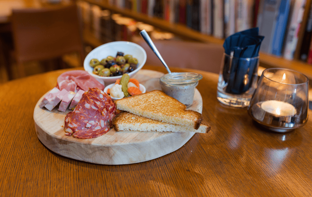 Plateau de charcuterie servi dans le cadre chaleureux du Library Bar de l’Hôtel Ambassade à Amsterdam.