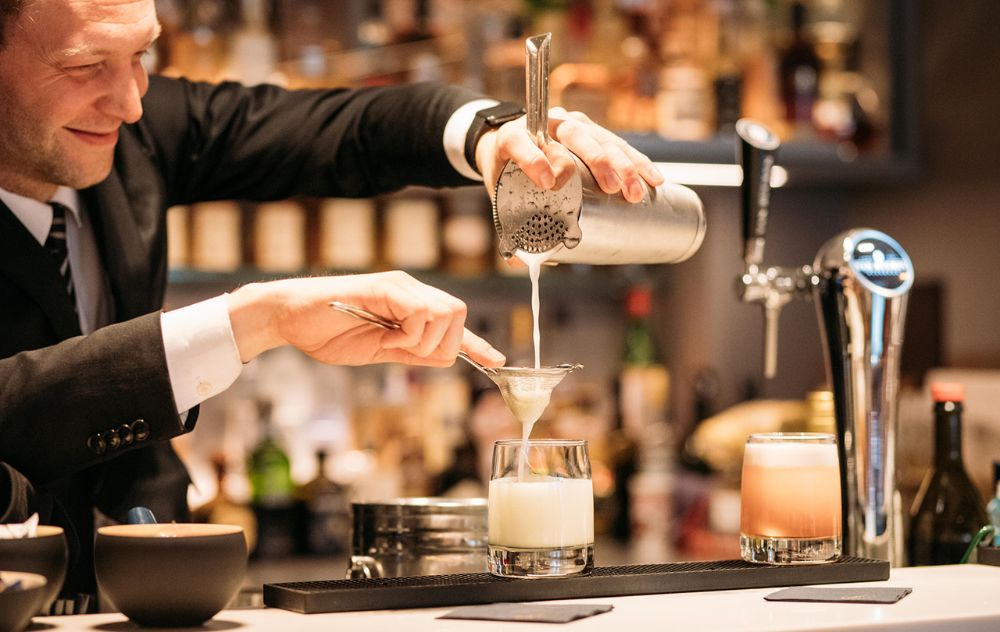 Barman préparant des cocktails au Library Bar de l’hôtel Ambassade, réputé pour ses boissons inventives et son cadre raffiné.