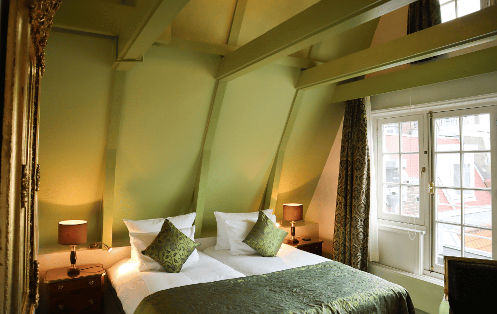 Chambre Deluxe Classic à l’Ambassade Hotel avec mobilier élégant et ambiance chaleureuse.