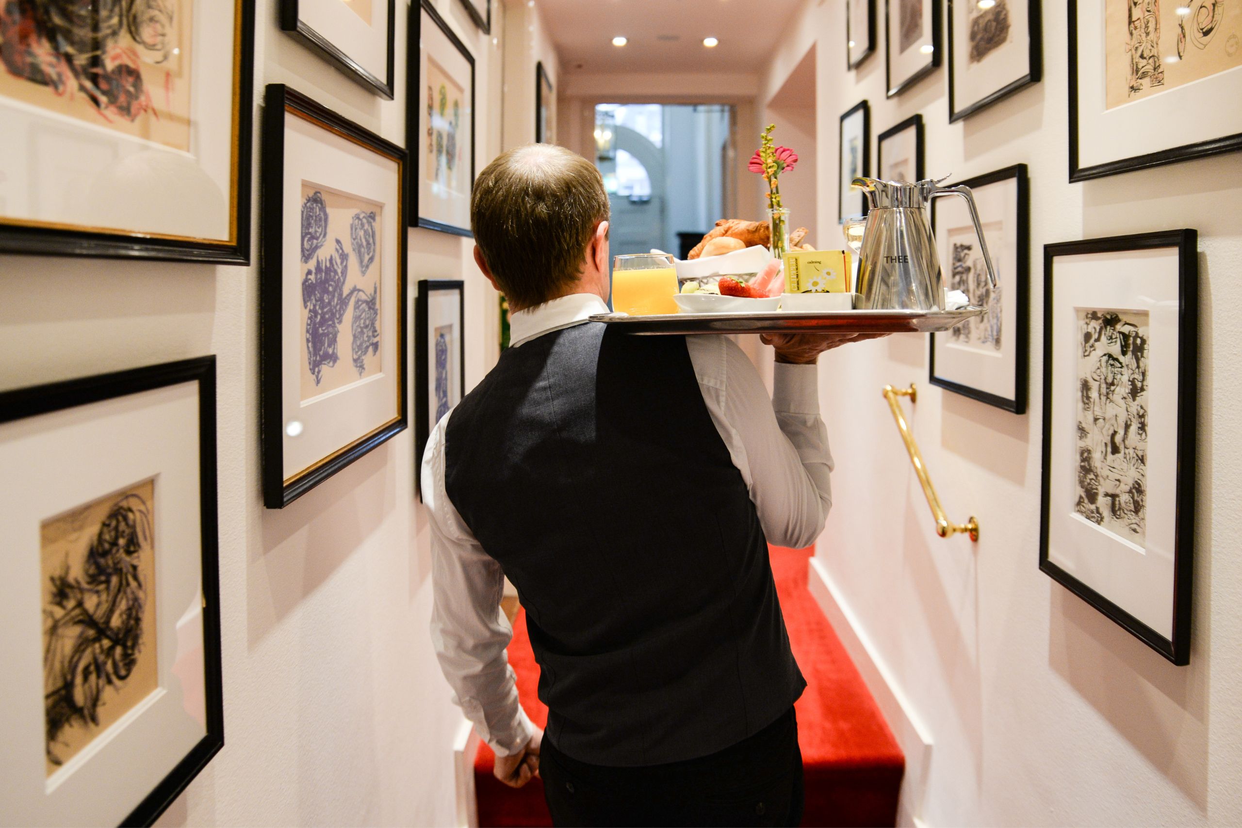 Hotel staff walking through corridor delivering breakfast room service at the ambassade hotel.