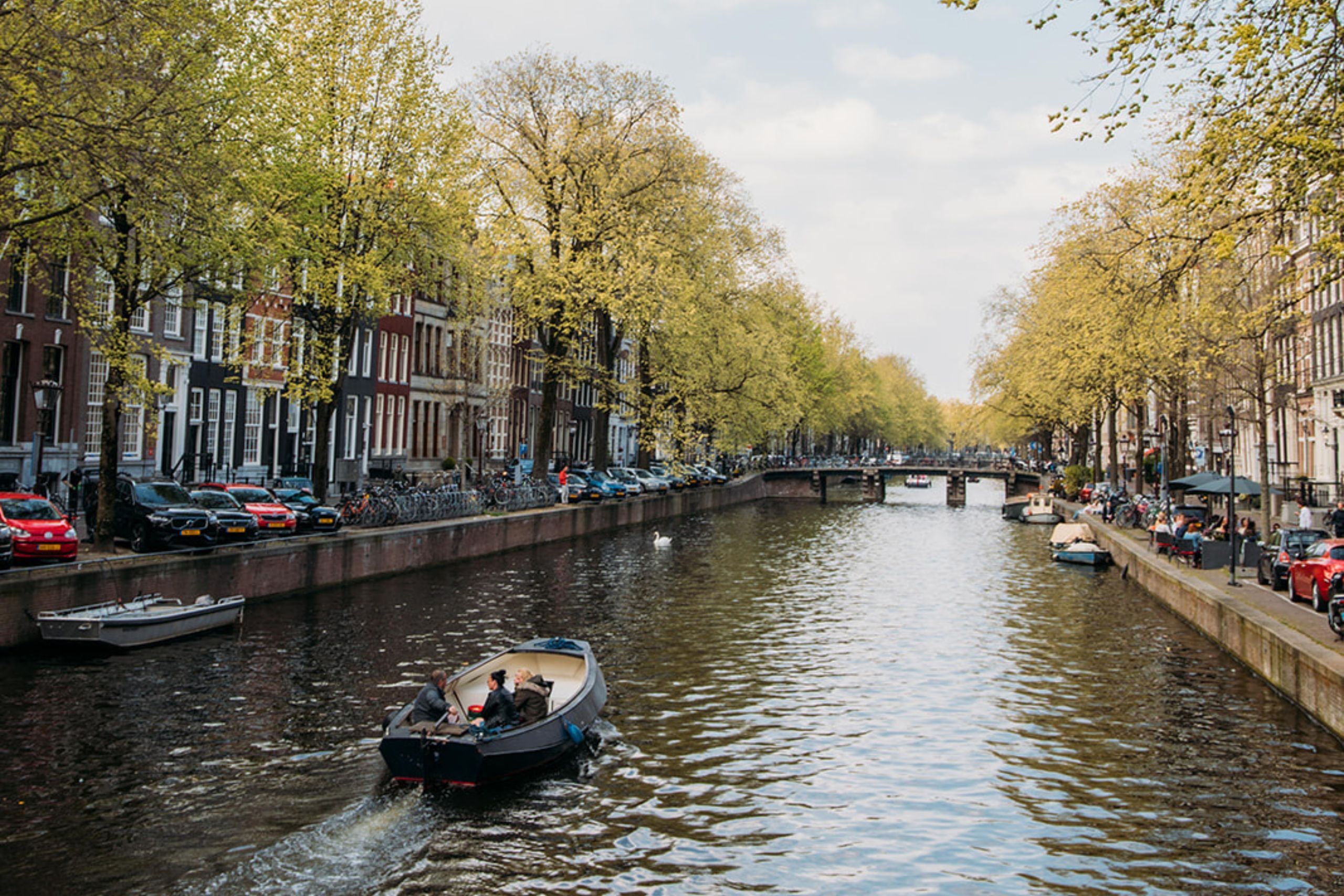 Historische grachtenpanden langs de Herengracht met een passerende boot.