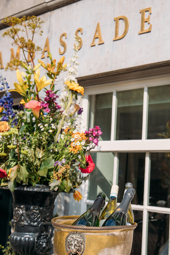 Façade de l’Ambassade Hôtel avec un magnifique bouquet de fleurs et un seau à vin avec du vin.