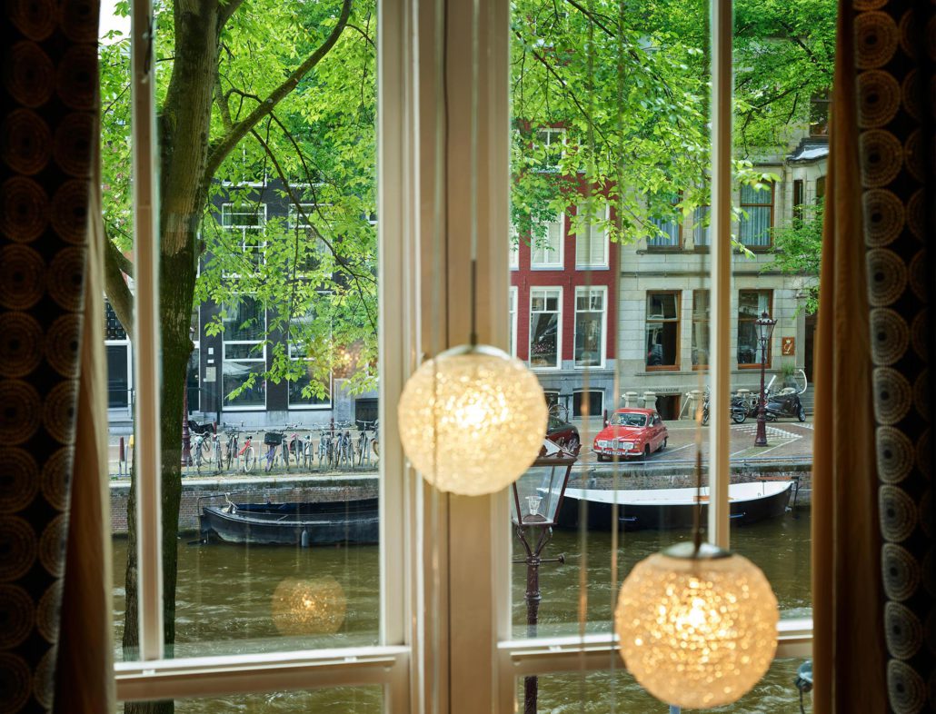 Grachtenzicht vanuit een raam van het Ambassade Hotel, met uitzicht op de historische Herengracht in Amsterdam.