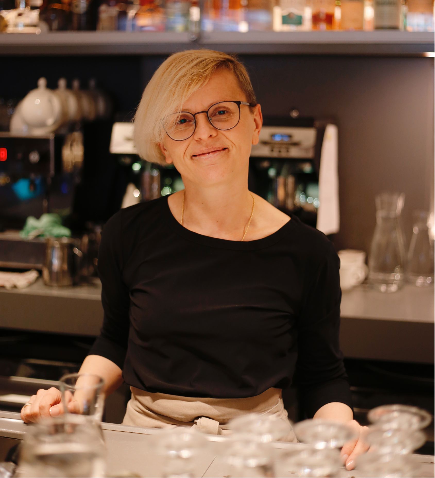 Lachende*r Mitarbeitende hinter der Library Bar im Ambassade Hotel.