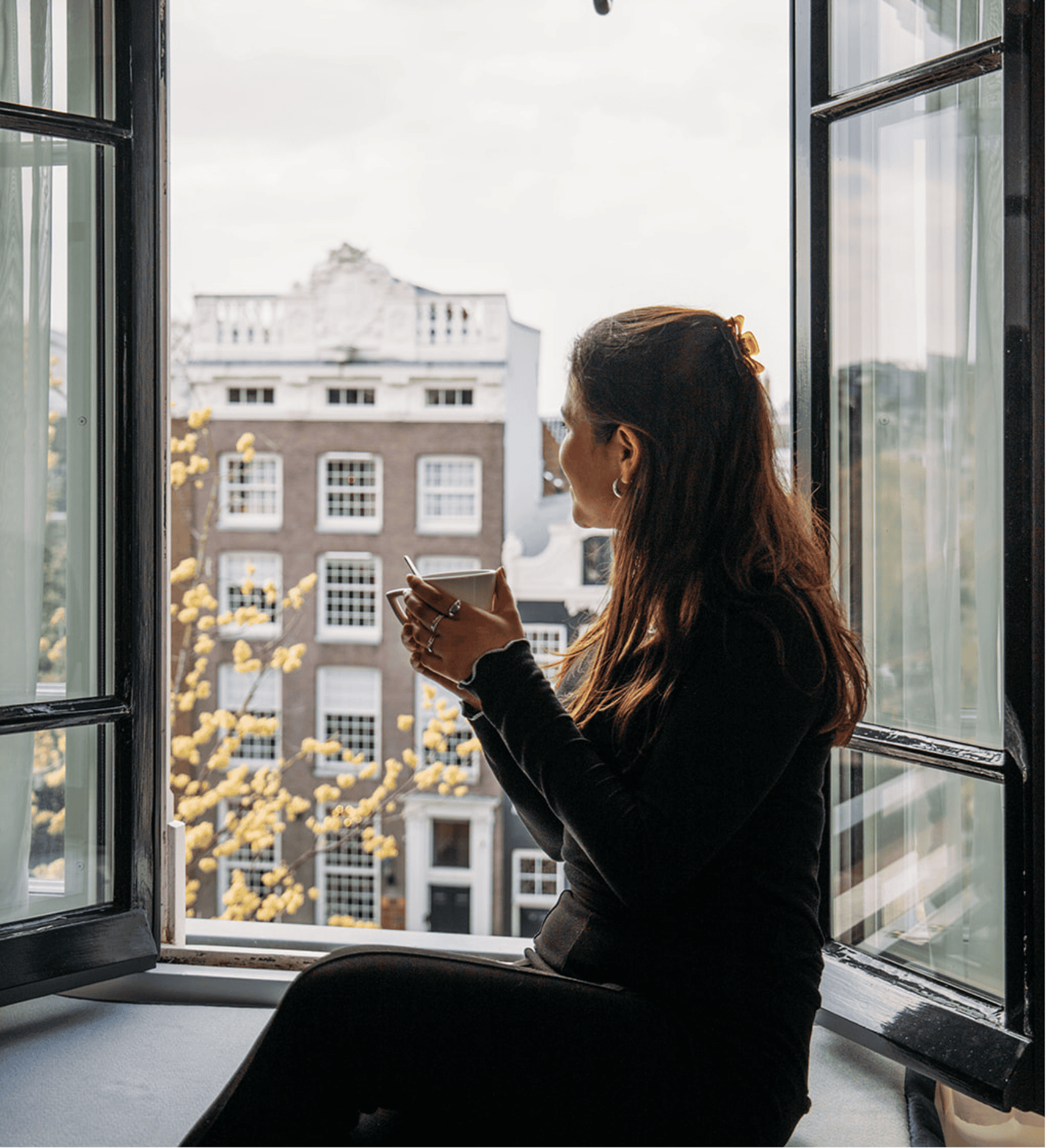 Vrouw geniet van het schilderachtige uitzicht op de gracht door het raam in het Ambassade Hotel in Amsterdam.