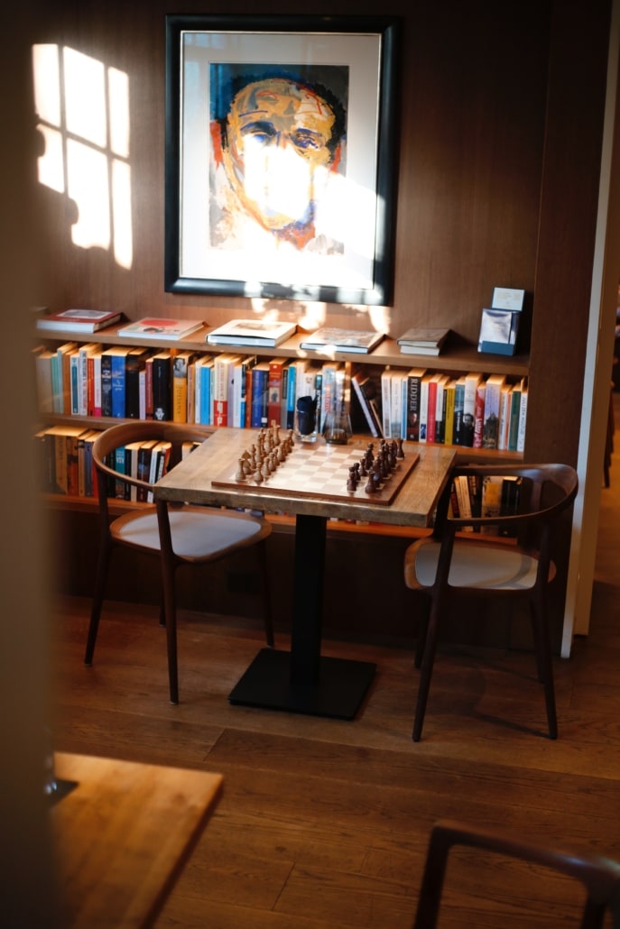 Table dans le Library Bar avec un échiquier, entourée d’art et de livres.