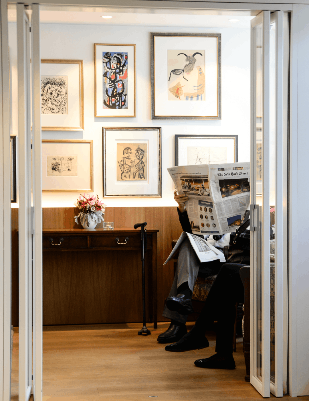 Gast liest eine Zeitung in der Cobra Lounge des Ambassade Hotels, umgeben von moderner Kunst.